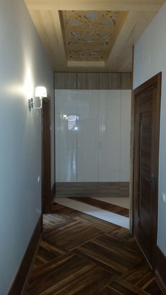 Widok wykończenia korytarza, tj. podłoga orzech, drzwi orzech, szafa garderobiana - fronty płyta biała akrylowa, sufit konstrukcja drewniana z drewna lipowego